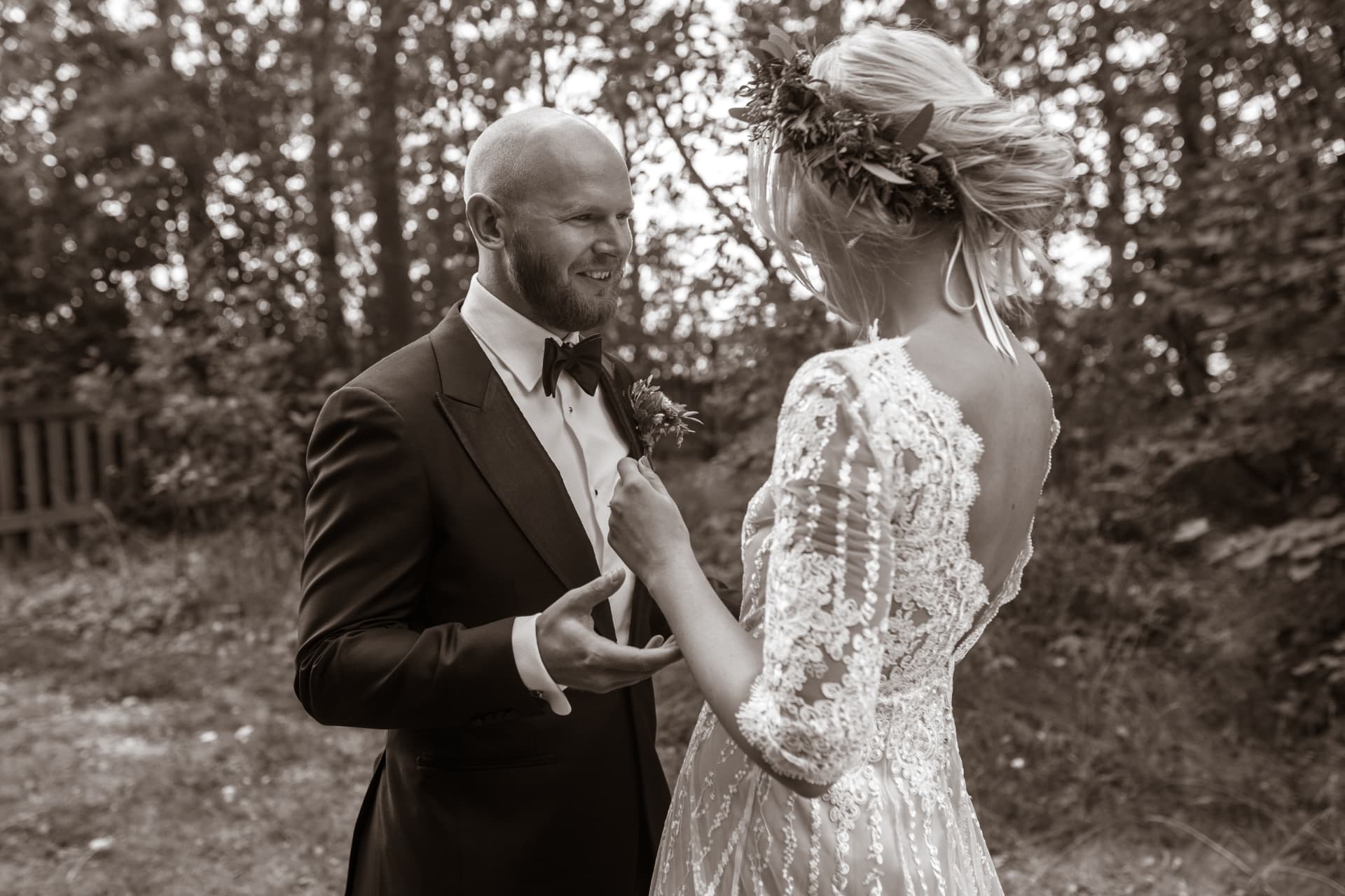 Bruden sätter fast brudgummens boutonnière, i sepiaton – bröllopsfoto av Mehmet Budak