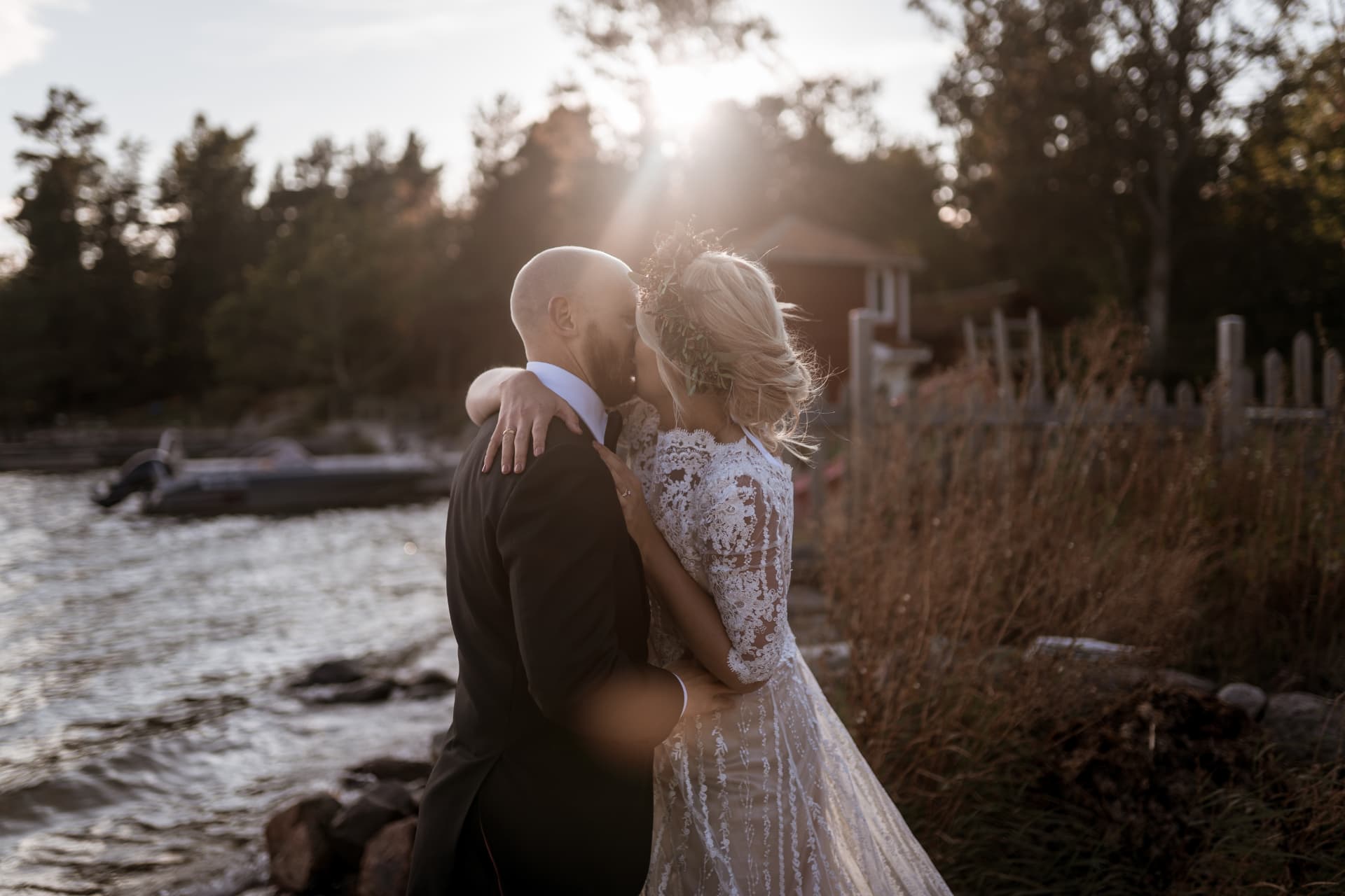 Brudparet kysser varandra i kvällssolen vid vattnet – bröllopsfoto av Mehmet Budak