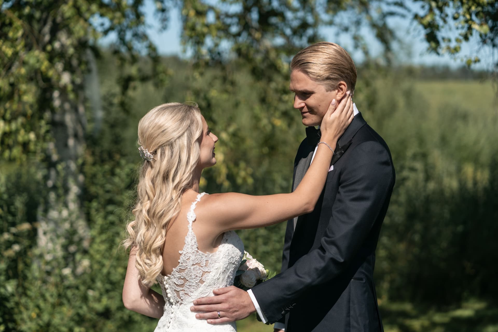 Brudparet möts med händerna om varandras ansikten i solskenet – bröllopsfoto av Mehmet Budak