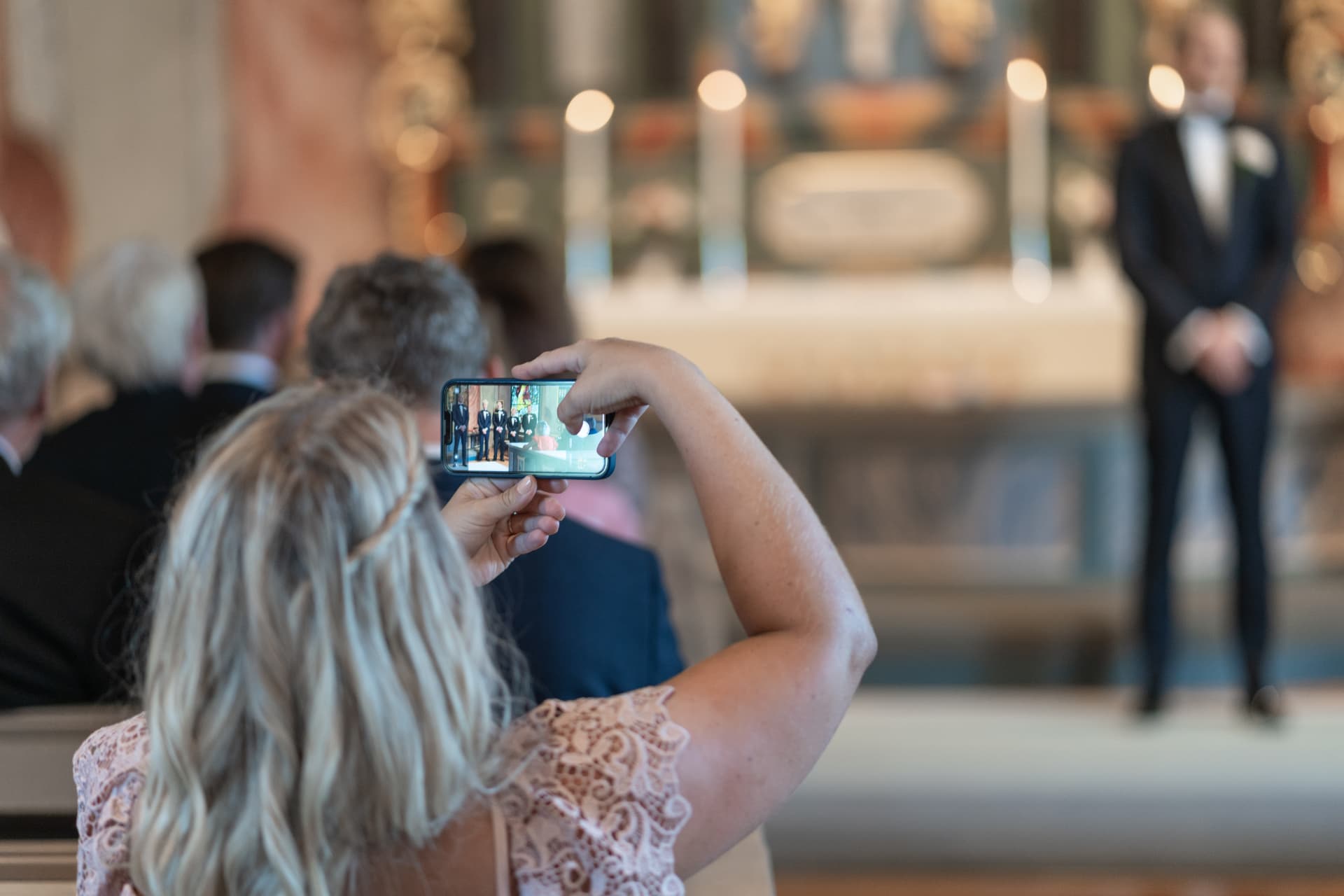 En gäst filmar vigseln med mobilen medan brudgummen väntar vid altaret – bröllopsfoto av Mehmet Budak