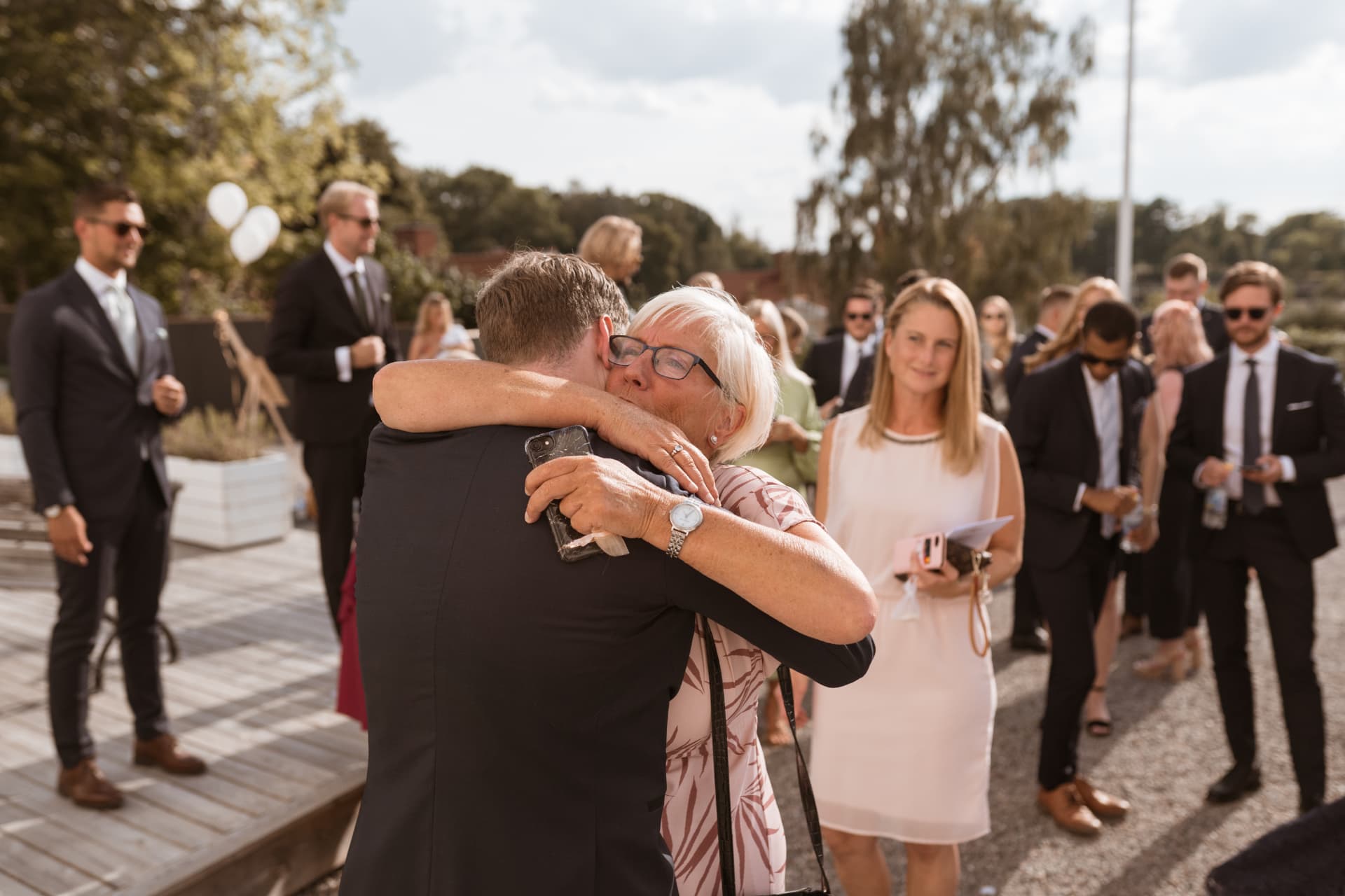 Brudgummen kramas av en gäst under gratulationerna – bröllopsfoto av Mehmet Budak