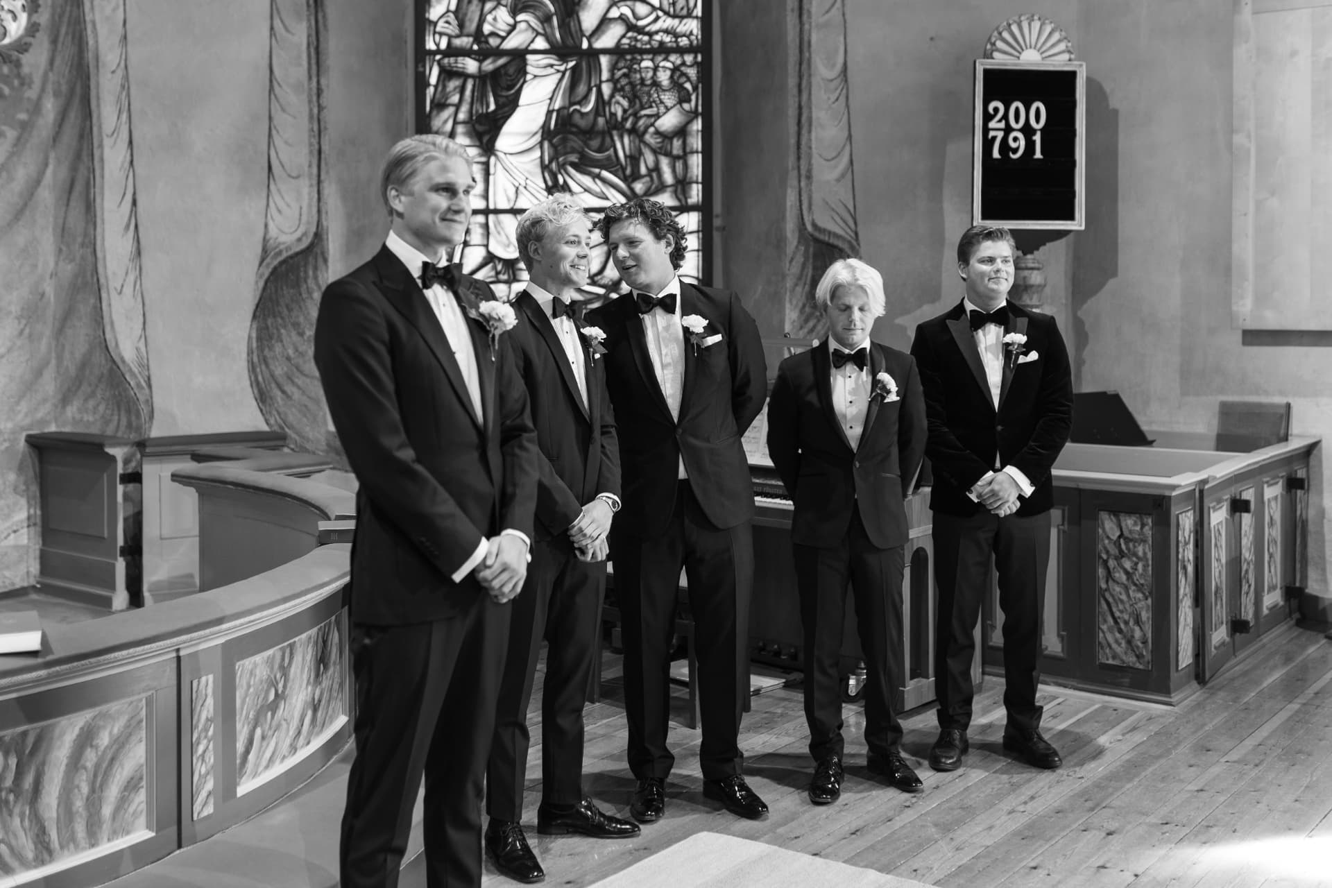 Brudgummen och marskalkarna uppställda i kyrkan, svartvitt – bröllopsfoto av Mehmet Budak