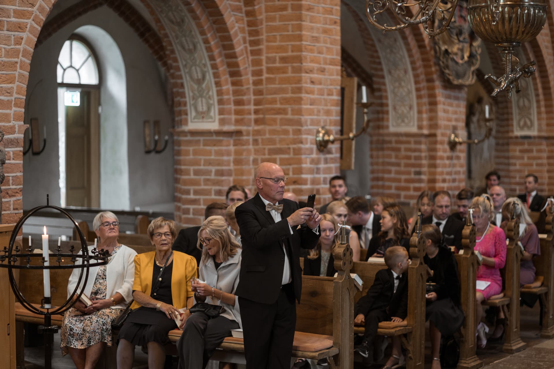 Gästerna sitter i kyrkbänkarna i väntan på vigseln – bröllopsfoto av Mehmet Budak