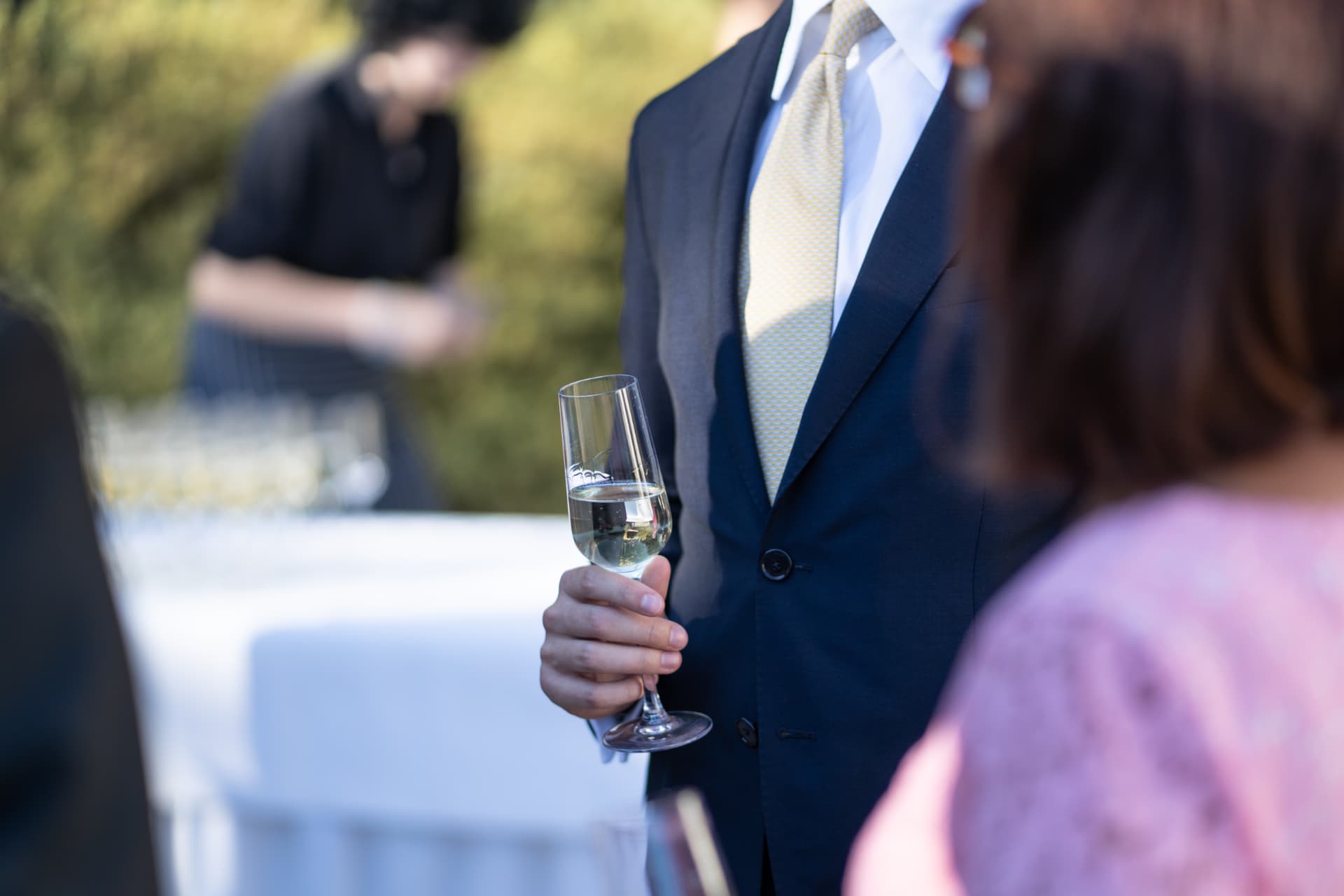 Närbild av en gäst som håller ett champagneglas under mottagningen – bröllopsfoto av Mehmet Budak