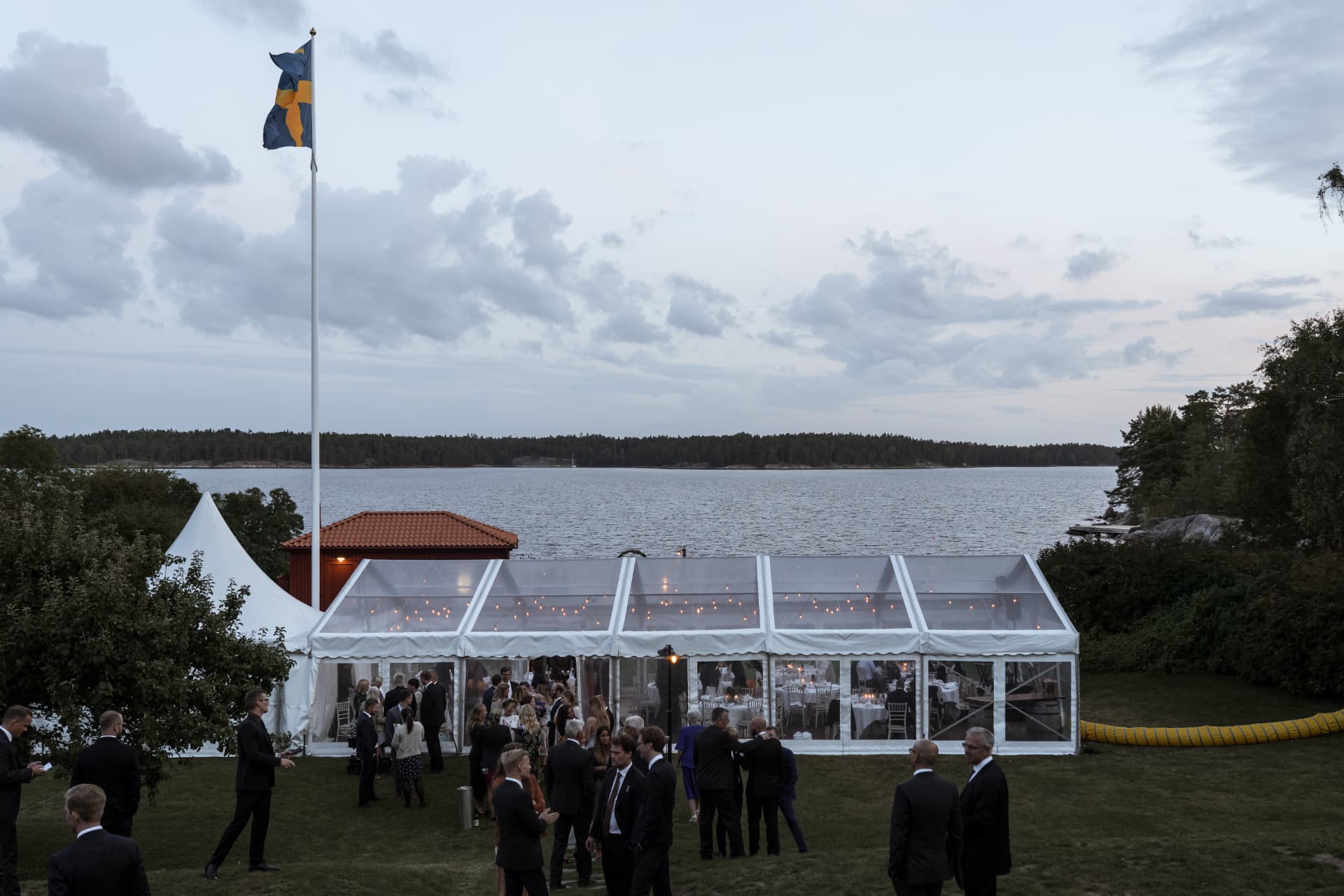 Festtältet vid vattnet i skymningen med svensk flagga – bröllopsfoto av Mehmet Budak