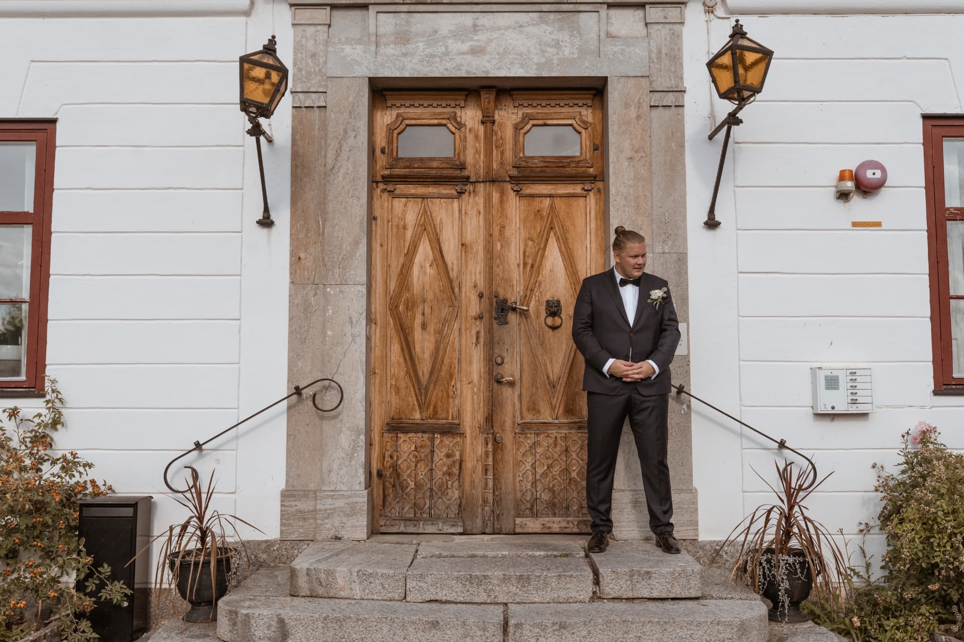 Best man väntar framför herrgårdens gamla trädörr – bröllopsfoto av Mehmet Budak