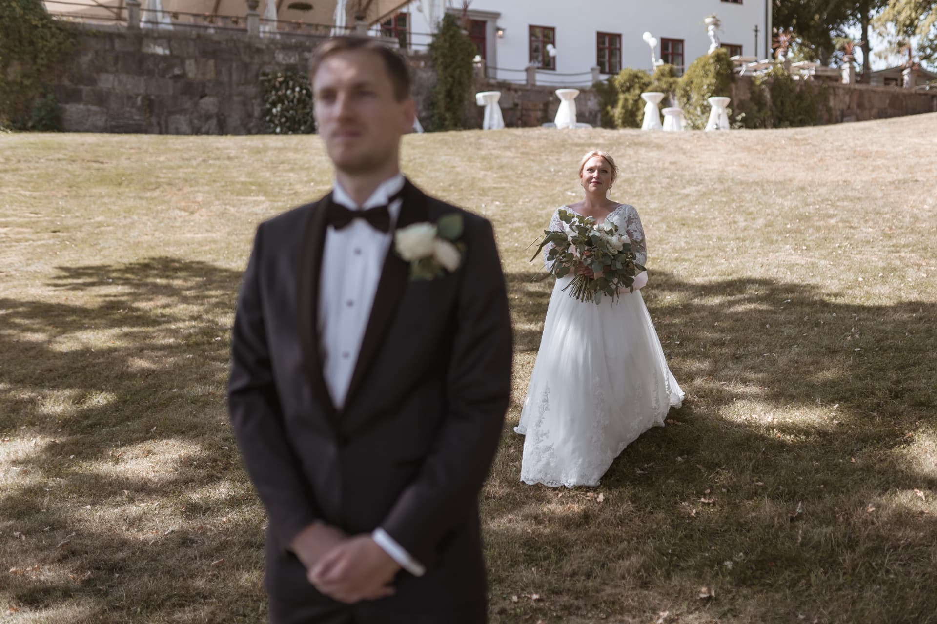 First look: bruden kommer gående mot brudgummen på herrgårdens gräsmatta – bröllopsfoto av Mehmet Budak
