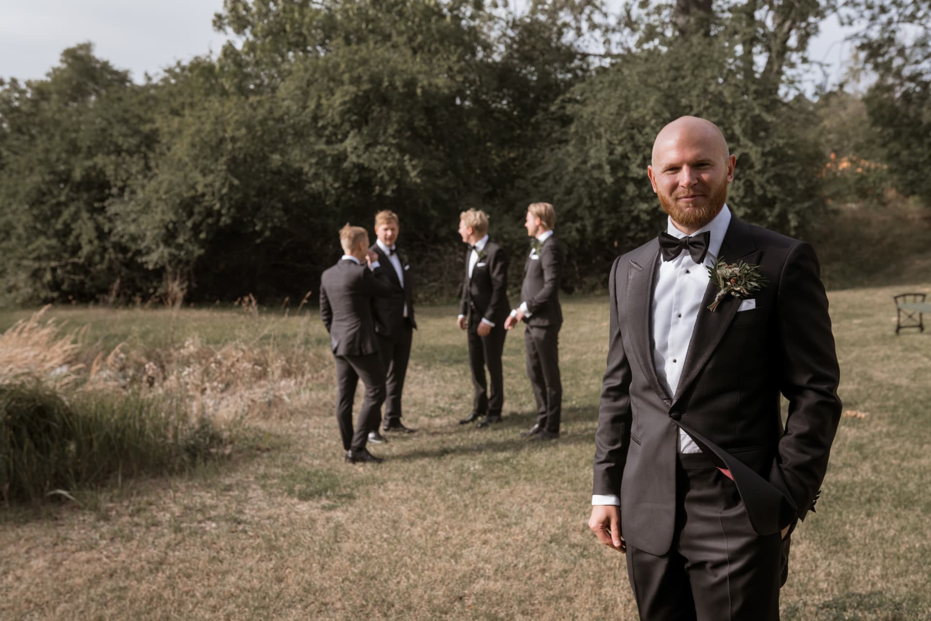 Porträtt av brudgummen med vännerna i bakgrunden – bröllopsfoto av Mehmet Budak