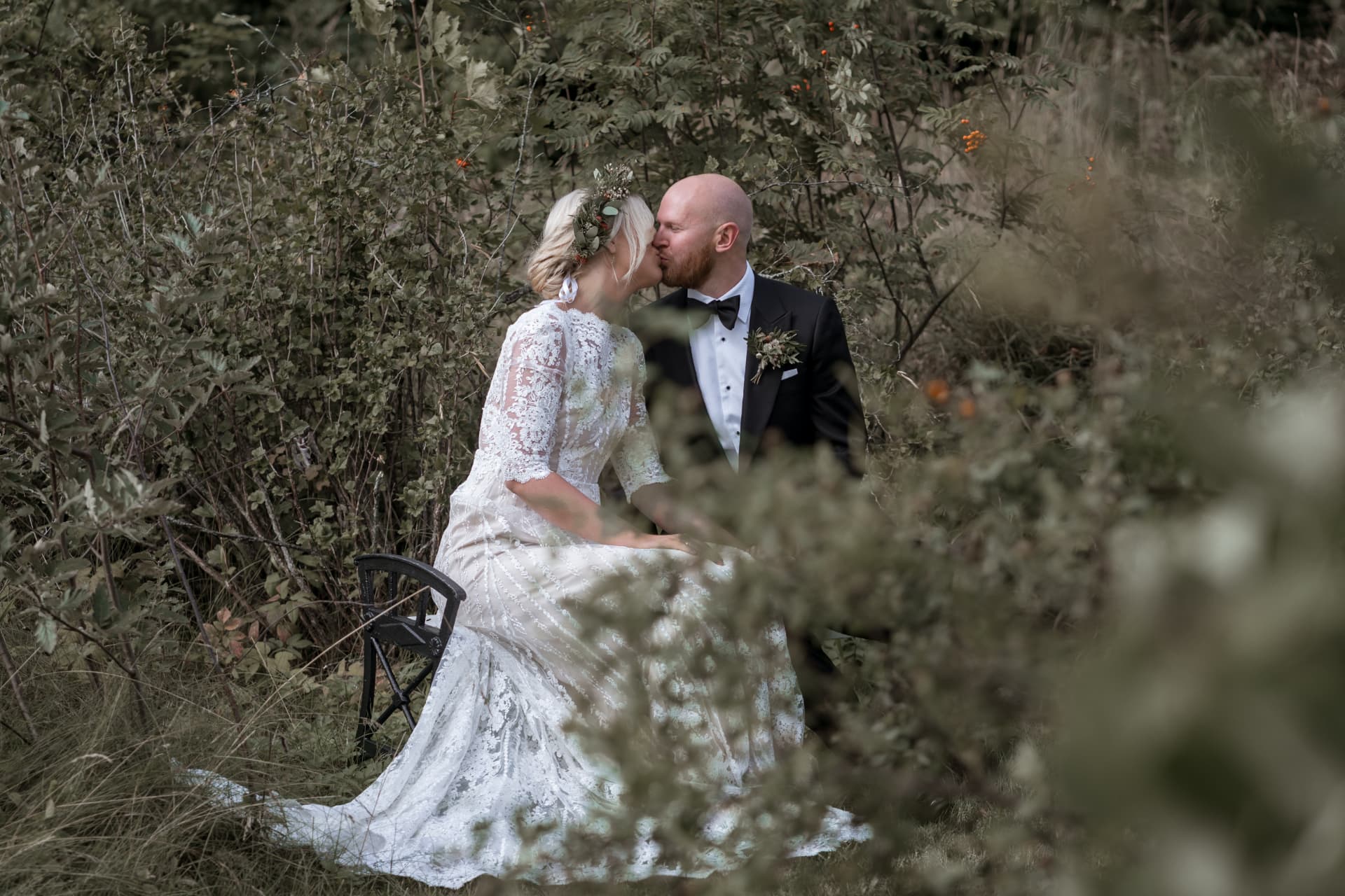 Brudparet kysser varandra bland buskar och högt gräs – bröllopsfoto av Mehmet Budak