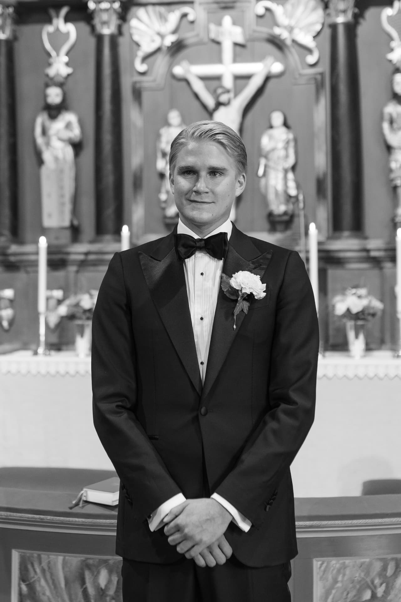 Porträtt av brudgummen i smoking framför altaret i kyrkan, svartvitt – bröllopsfoto av Mehmet Budak
