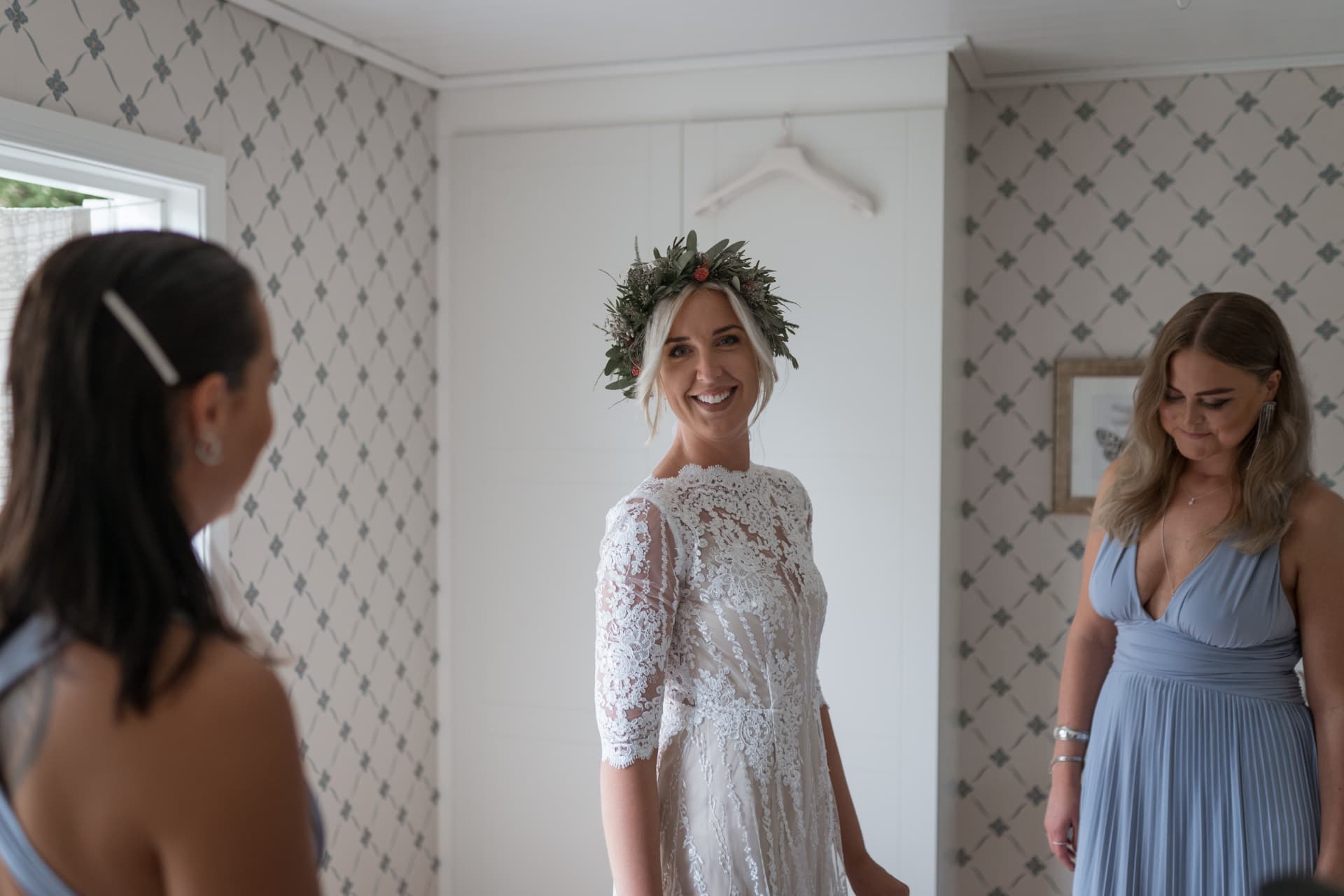 Bruden i klänning och blomsterkrans ler mot tärnorna – bröllopsfoto av Mehmet Budak