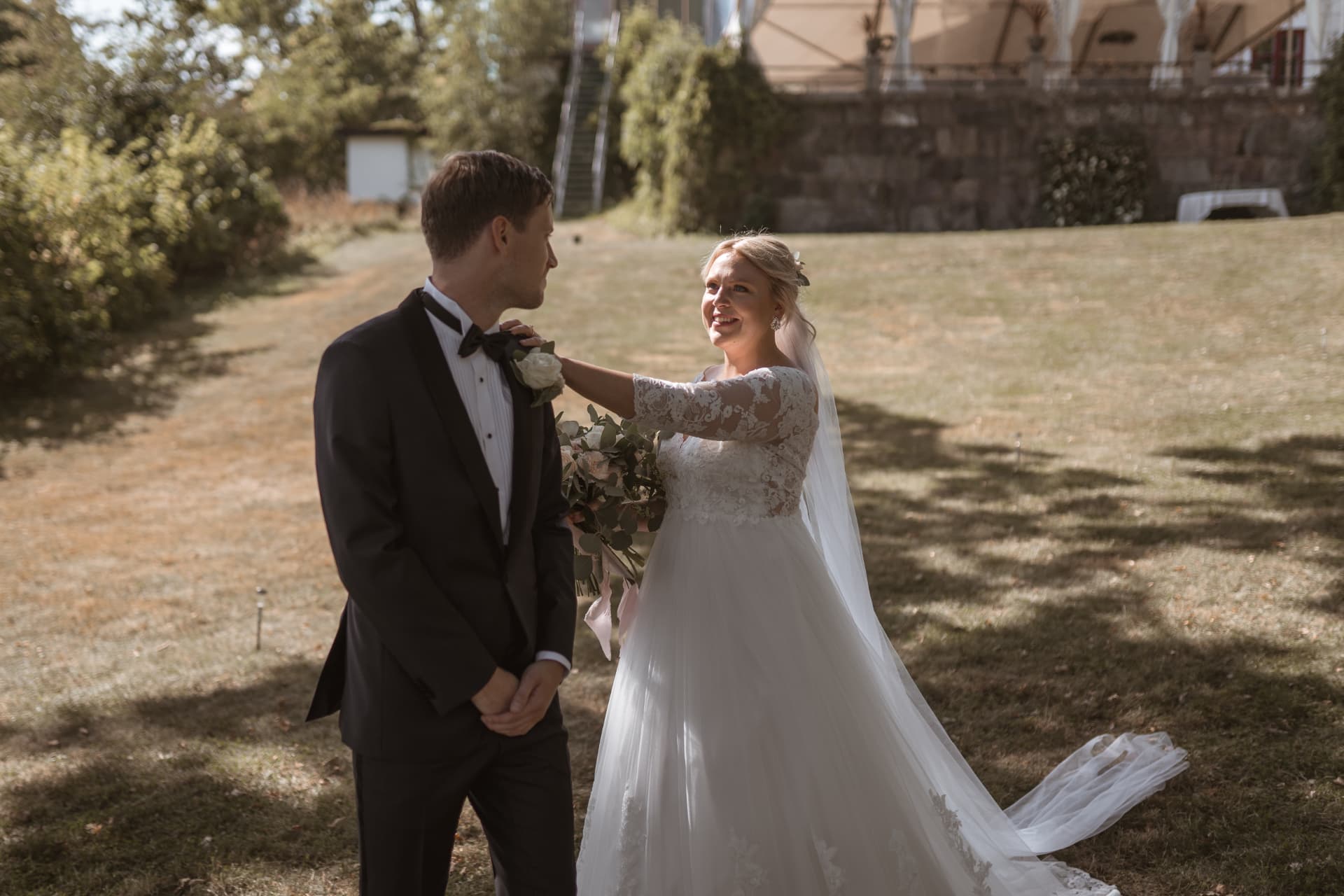 First look: bruden lägger handen på brudgummens axel på gräsmattan vid herrgården – bröllopsfoto av Mehmet Budak