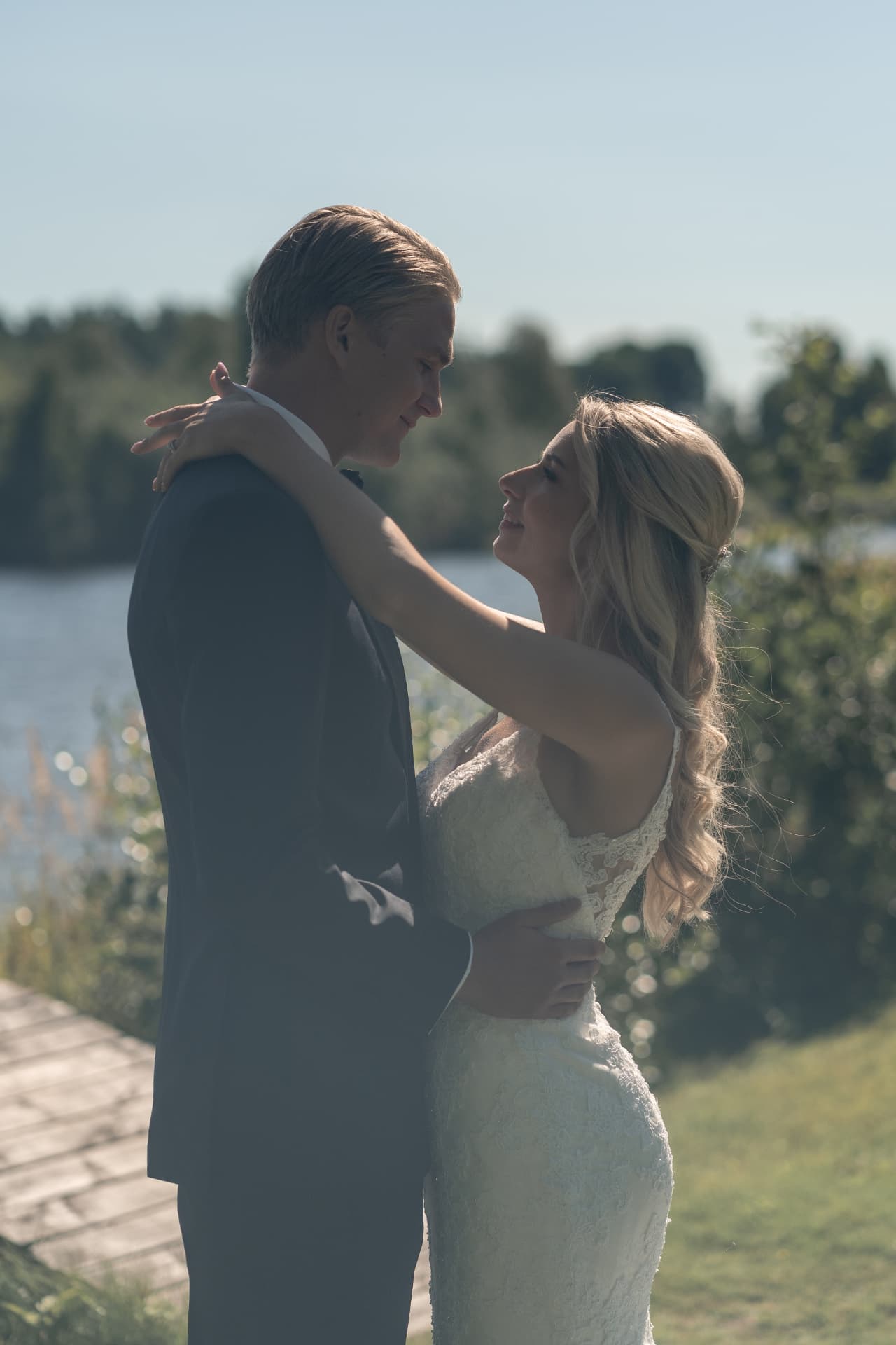 Brudparet omfamnar varandra i motljus vid sjön i Sunne – bröllopsfoto av Mehmet Budak