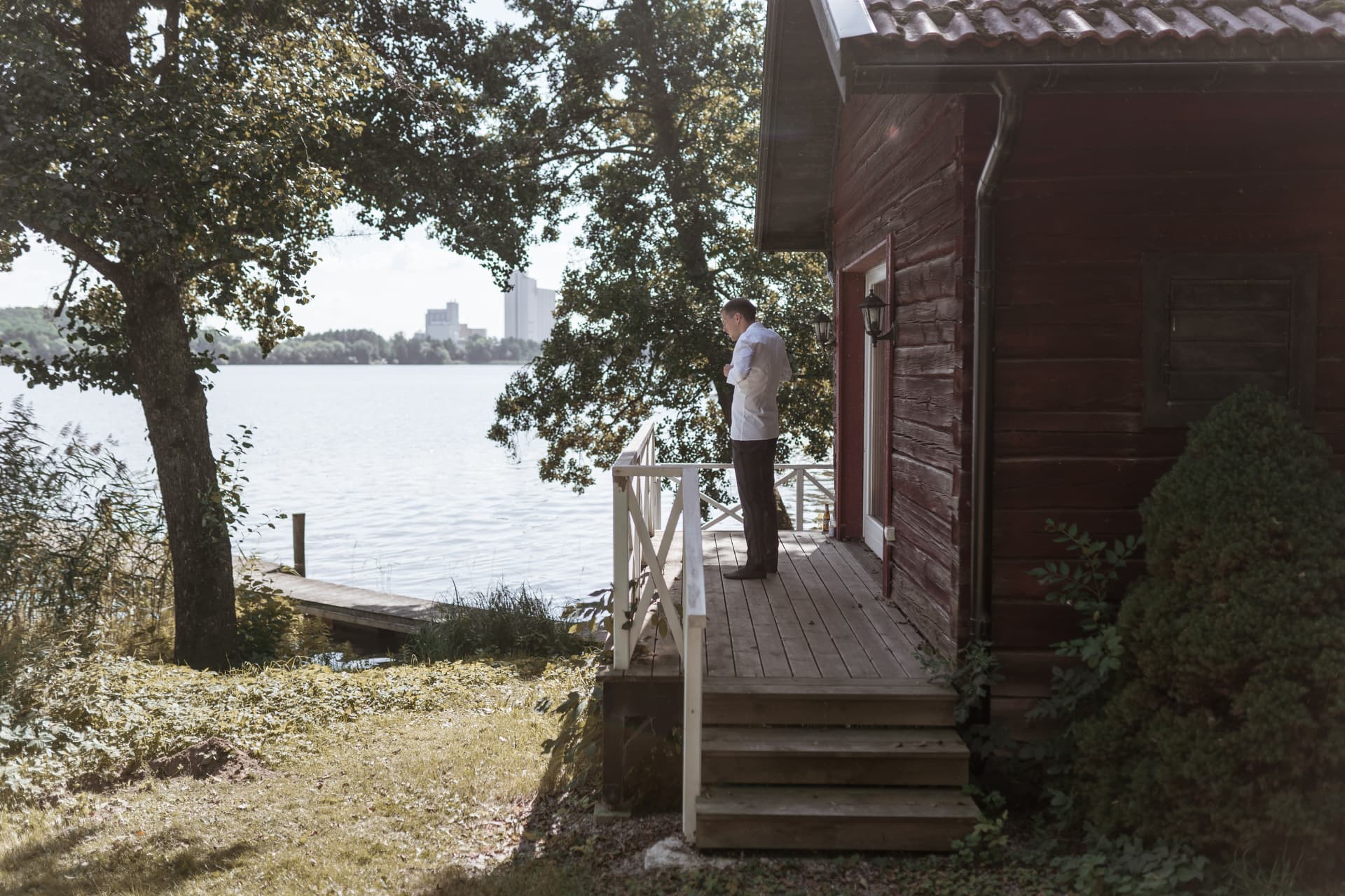 Brudgummen på verandan med utsikt över vattnet – bröllopsfoto av Mehmet Budak