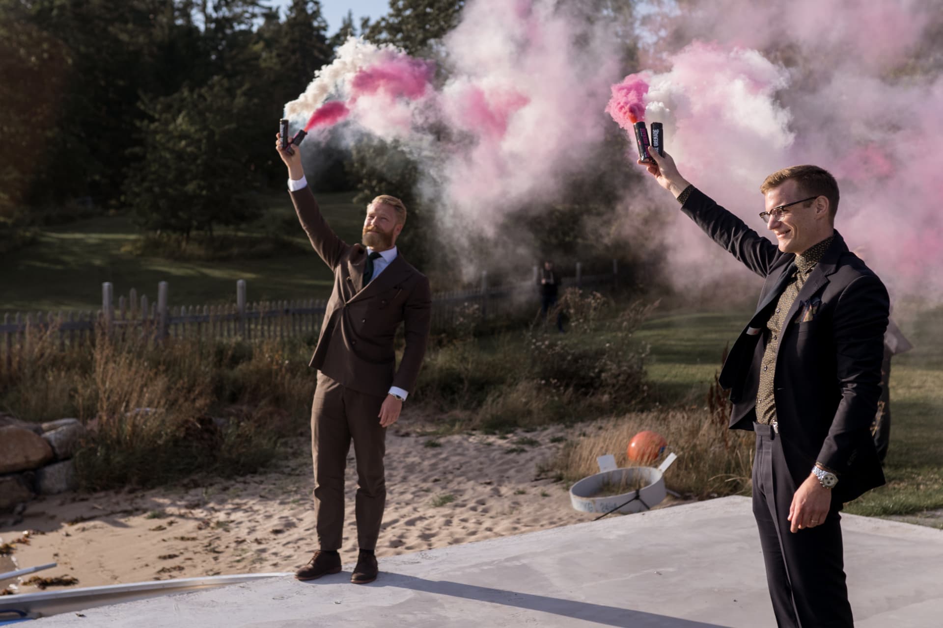 Två gäster med rosa rökbloss vid vattnet – bröllopsfoto av Mehmet Budak