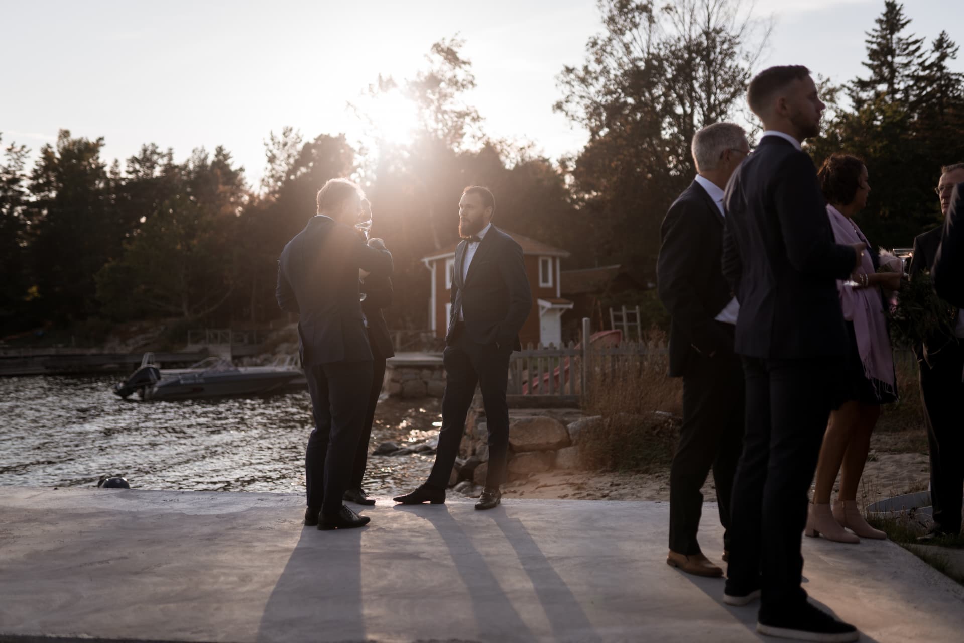 Gäster minglar i motljus vid bryggan – bröllopsfoto av Mehmet Budak