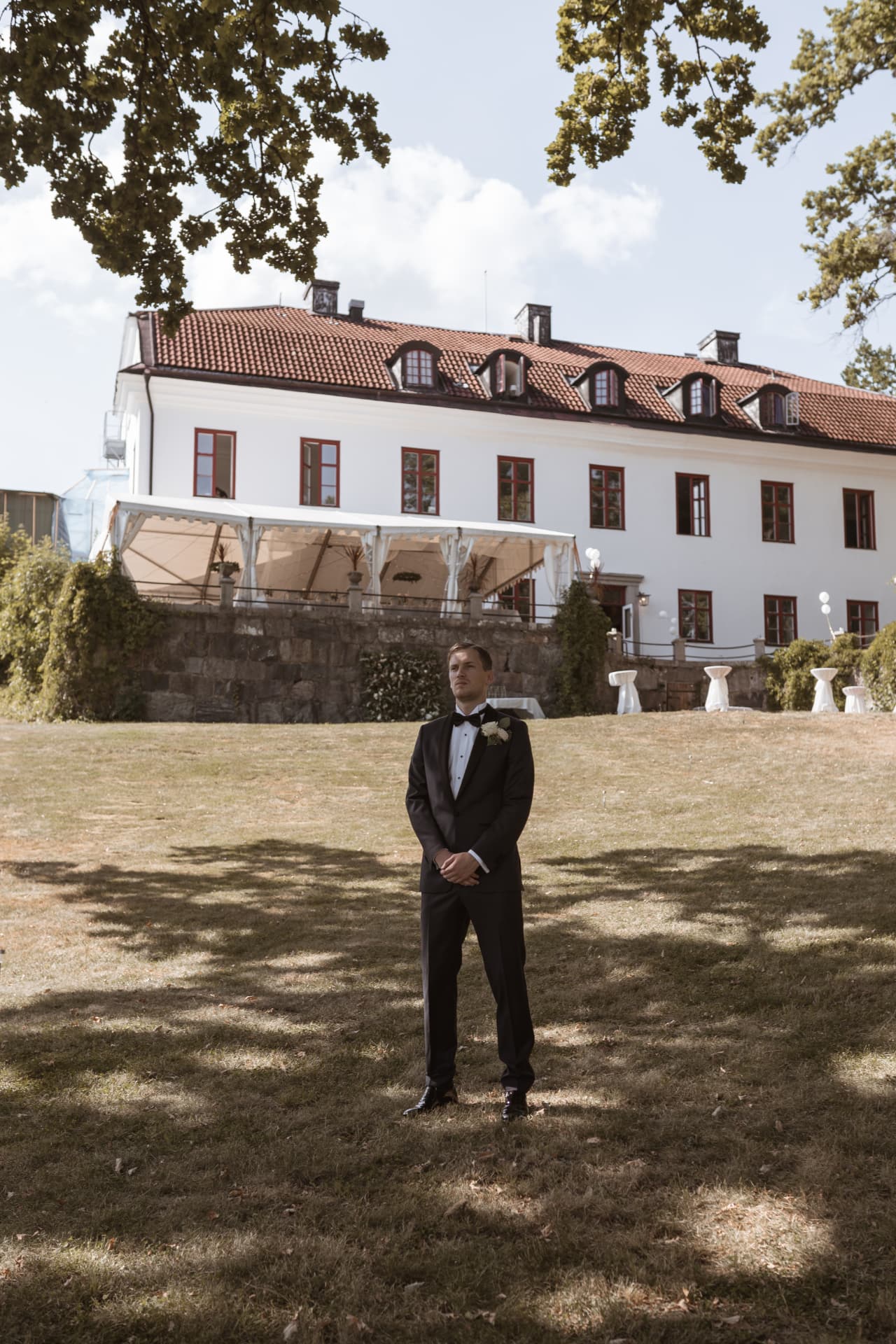 Brudgummen väntar på gräsmattan framför Ulvhälls Herrgård – bröllopsfoto av Mehmet Budak