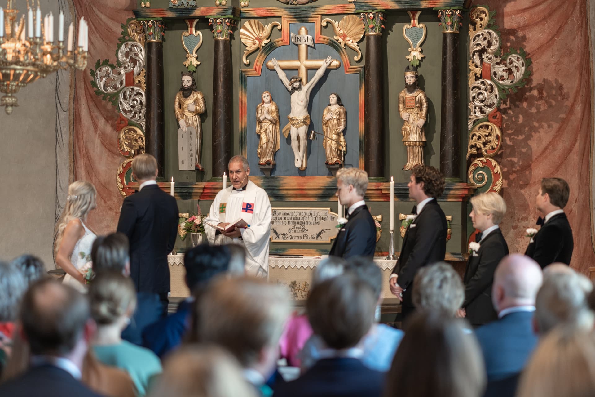 Prästen talar till brudparet och gästerna i den dekorerade kyrkan – bröllopsfoto av Mehmet Budak