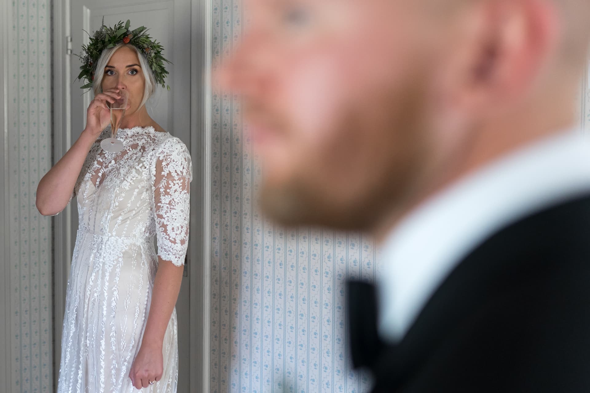 Bruden dricker champagne med brudgummen i förgrunden – bröllopsfoto av Mehmet Budak